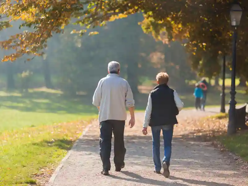 Senior citizen couple taking a walk in a park during autumn morning.