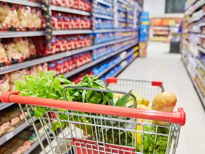 Shopping cart full groceries in a grocery store aisle.