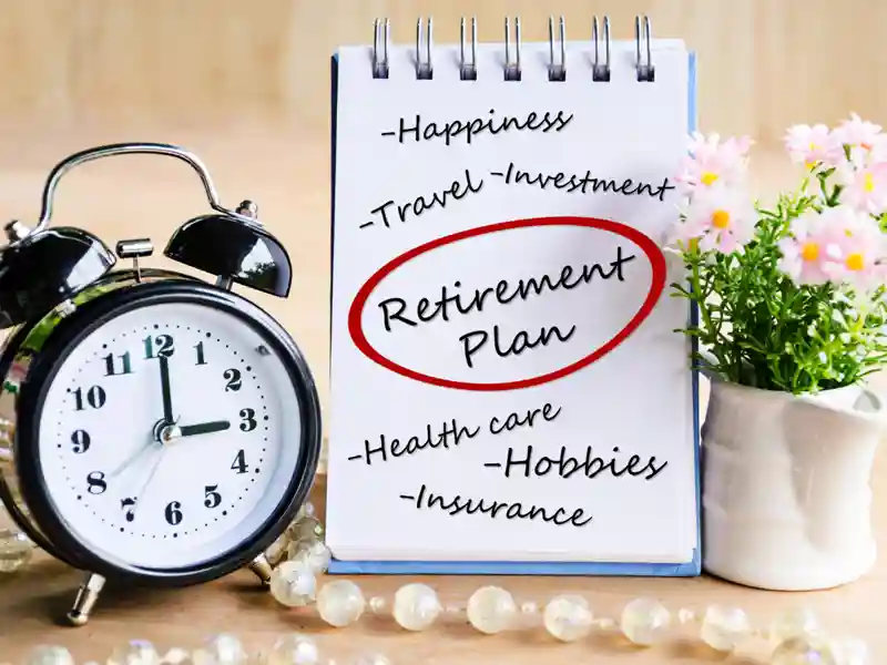 A notepad with the words "Retirement Plan" circled, placed next to an alarm clock and a small white vase with a plant.