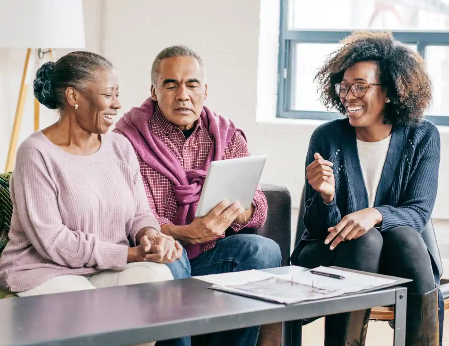 Elderly couple and daughter sitting in a living room, smiling.
