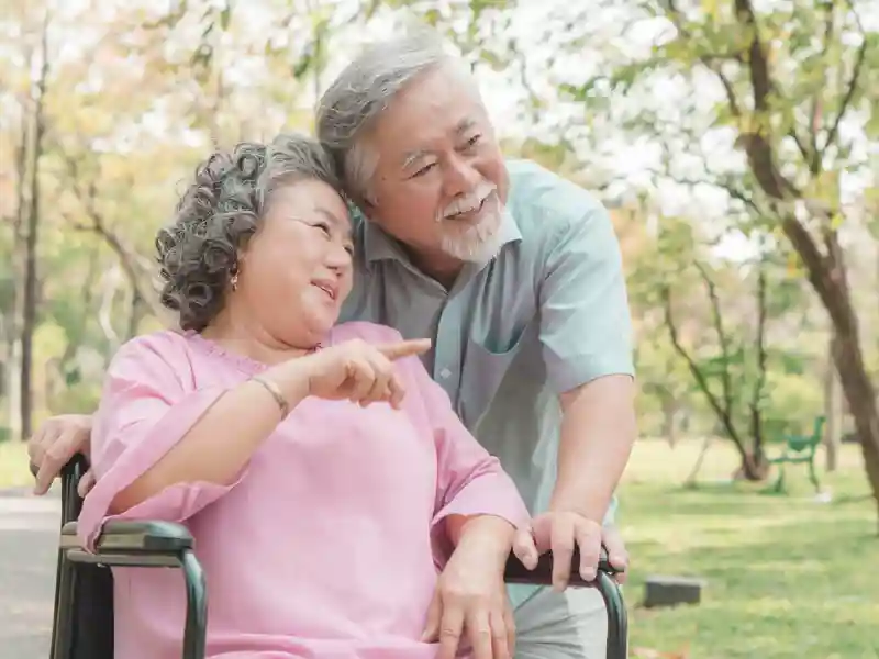 Asian senior couple embracing together in the park in the morning.
