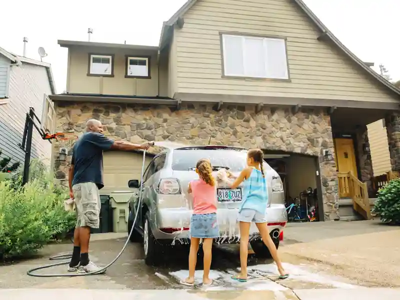 Father and daughters washing car.