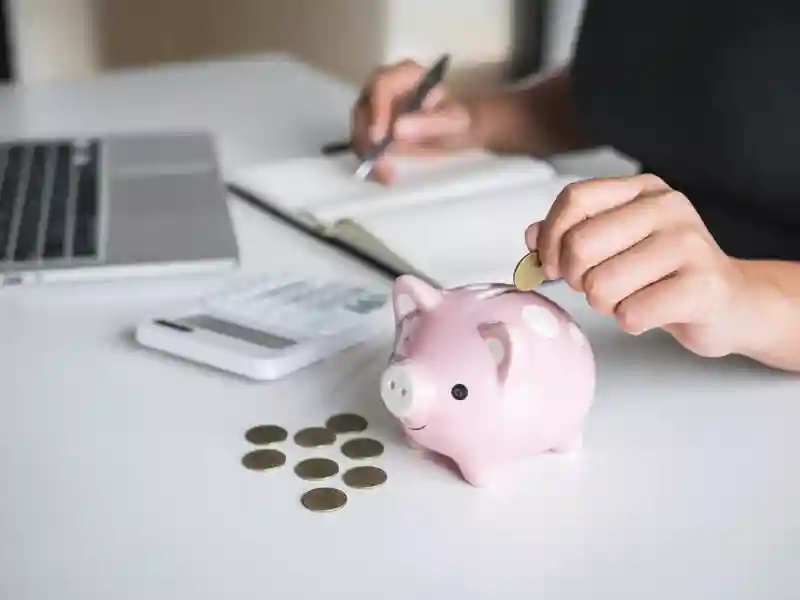 Woman putting golden coin in pink piggy bank while doing finances.