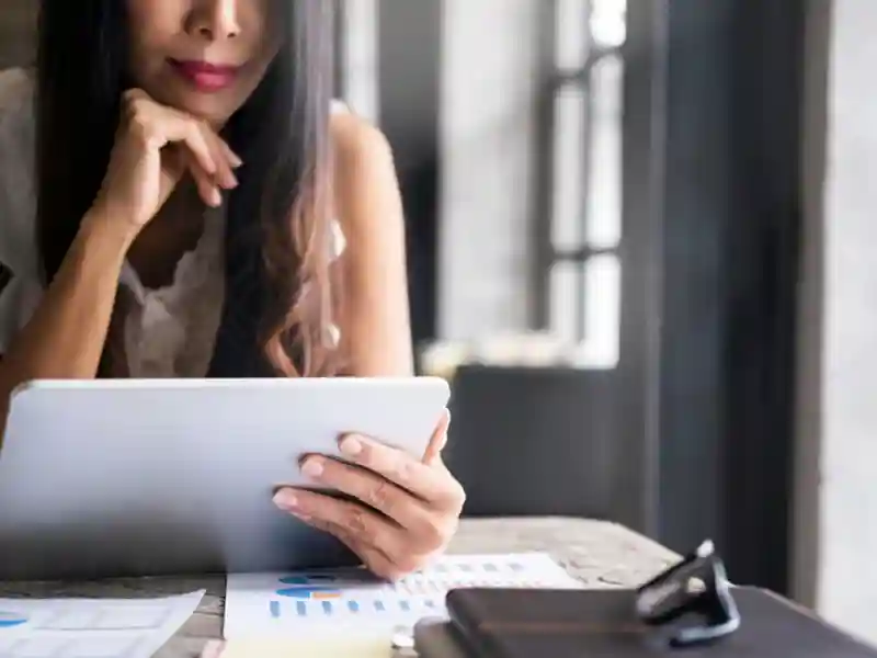 A woman sitting and viewing funds on her tablet
