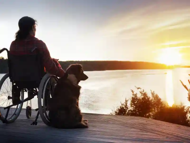 Woman in wheelchair with her dog at sunset.
