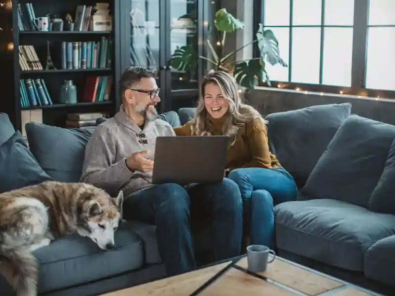 Mature couple at home using video call to talk with friends.