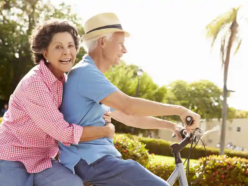 Senior couple riding a bicylce in the park.