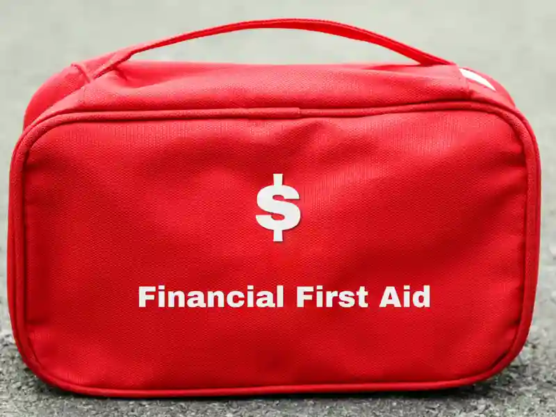 A red first aid bag labeled "Financial First Aid," placed on a road.