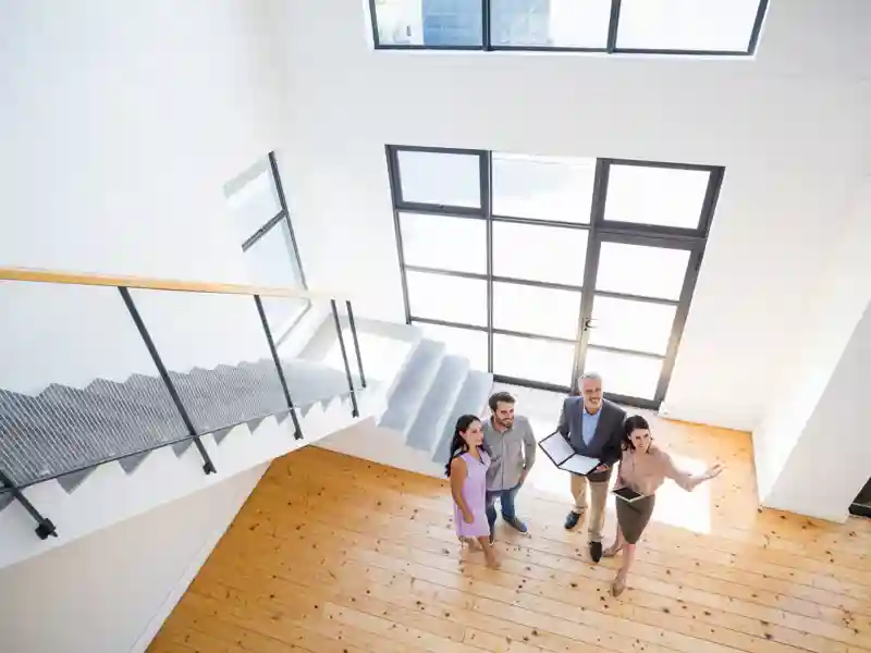 Real estate agent showing new house to couple with digital tablet.