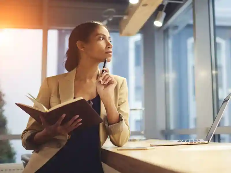 Female executive thinking over working schedule for employee writing report into notebook.