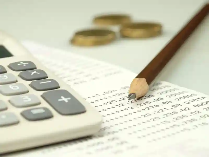 Close up of a pencil and calculator next to a bank statement.