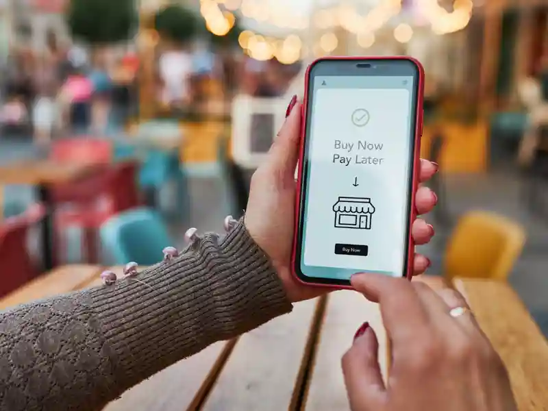 Woman holding out a phone showing credit card payment options.