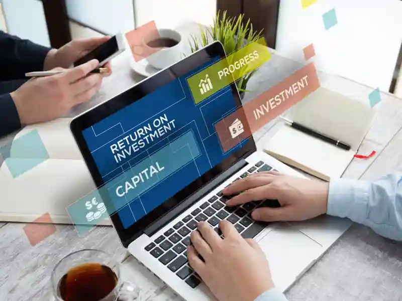 Financial advisor sitting at laptop with various investment terms on the screen.